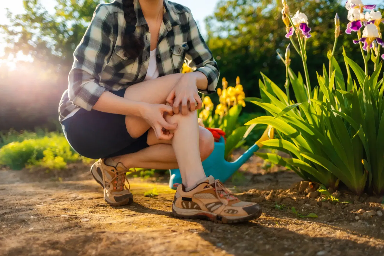 Frau im Garten kratzt an Mückenstich am Bein